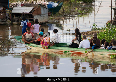 People in a public boat by a floating village in the Tonle Sap; Siem Reap, Cambodia Stock Photo