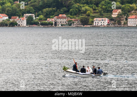 A small motorboat ferrying a bride and groom across the water in the Bay of Kotor; Perast, Kotor Municipality, Montenegro Stock Photo