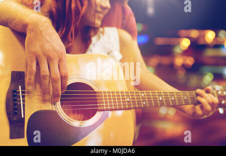 close up of couple with guitar over night lights Stock Photo