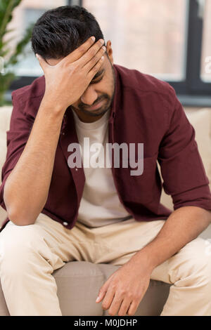 unhappy man suffering from head ache at home Stock Photo