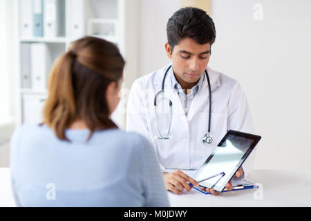 doctor showing tablet pc to patient at clinic Stock Photo