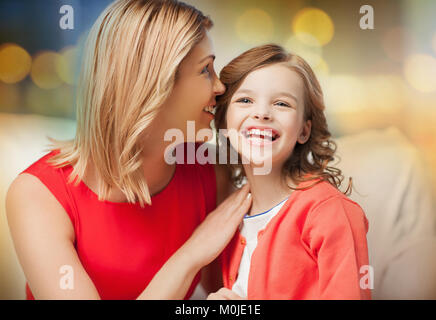 happy mother and girl whispering into ear Stock Photo