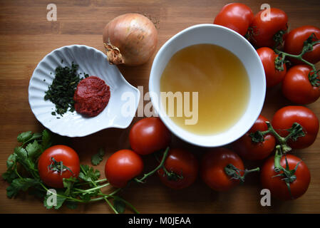 overhead food photography view of ingredients for home made tomato soup on a rustic wood board background with vegetables and fresh herbs Stock Photo