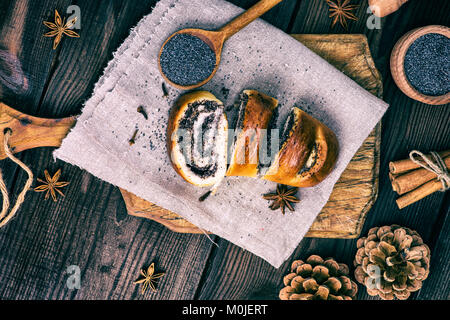 homemade roll with poppy seeds on a brown wooden board, top view, vintage toning Stock Photo