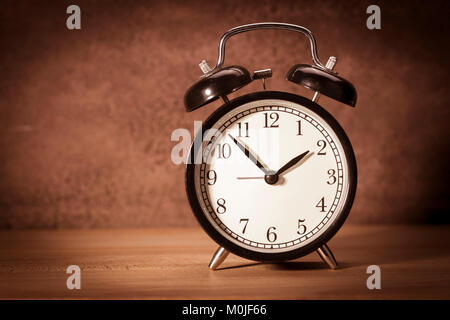 Clock - Vintage old alarm clock on sackings and a wooden background. Toned Stock Photo