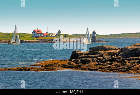 A pair of sailboats passing Ram Island Light as seen from Ociean Point, Maine near Boothbay, USA Stock Photo