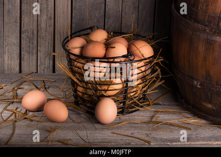 Brown chicken eggs in a basket and on a rustic wooden surface Stock Photo