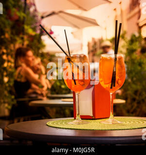 Aperol Spritz Cocktail. Alcoholic beverage based on table with ice cubes and oranges. Stock Photo