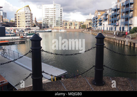 A view of Limehouse Basin,east London with iron posts and chain link barriers in the foreground and residential properties in the background Stock Photo