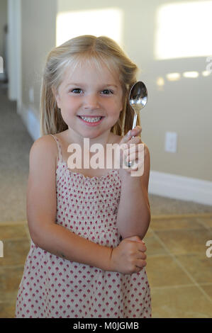 A beautiful,smiling,blonde girdle holding up a spoon Stock Photo