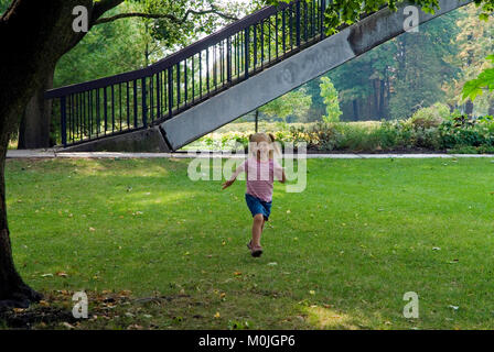 a young blond girl running in a park Stock Photo