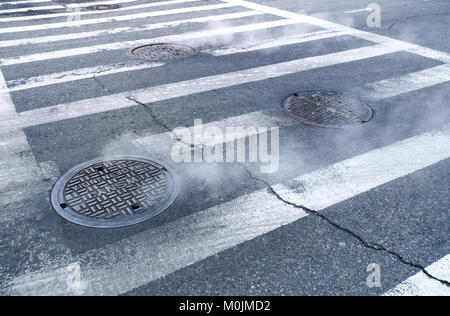 Steam coming from manhole covers in New York City Stock Photo