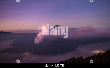 Volcanic landscape at sunrise with starry sky, smoking volcano Gunung Bromo, with Mt. Batok, Mt. Kursi, Mt. Gunung Semeru, Stock Photo