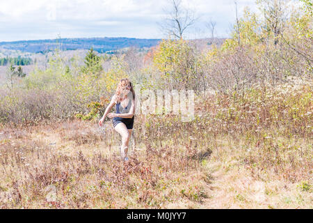Young athletic, fit, free happy woman running jogging jumping in autumn, fall, summer meadow field path hike in mid-air, muscles Stock Photo