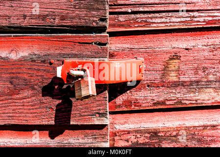 Macro closeup of retro vintage red wooden barn, shed exterior with locked doors and peeling old paint Stock Photo