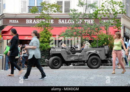 Wartime US Jeep in Paris, outside The Salons de thé brasserie in the Montmartre district of Paris, France with Jeep in monochrome. Time warp concept Stock Photo