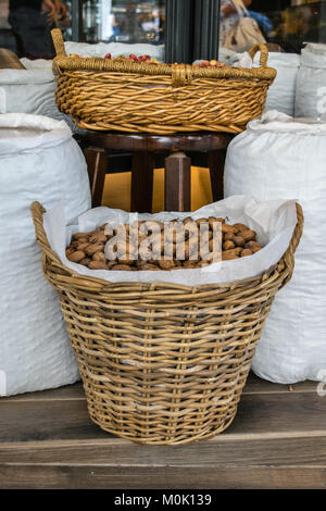 Unshelled pecans in a basket wrapped with white burlap textile, in front of the store Stock Photo