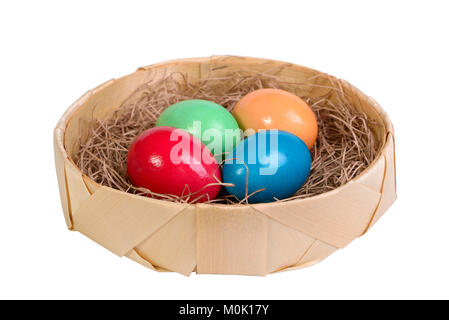 Four multi-colored eggs on straw in a wicker basket isolated on white Stock Photo