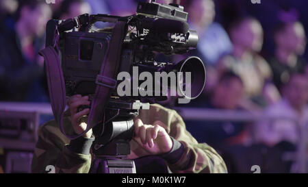 Cameraman using black professional digital video camera. Setup and working. Professional cameraman with headphones with camcorder in live television. Stock Photo