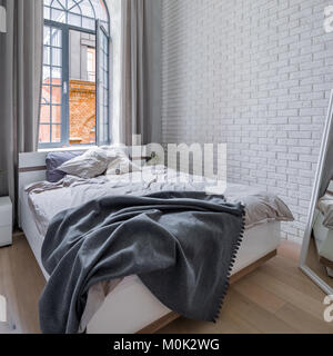 Loft bedroom with white brick wall, double bed and window Stock Photo