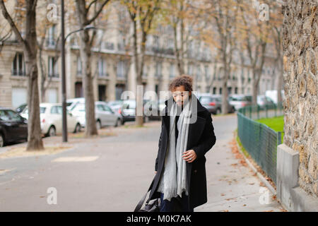 Attractive mulatto guy leaving city and going to railway station. Handsome man in black coat looks attractive. Concept of walking, hurrying and autumn Stock Photo