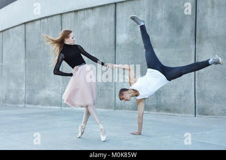 A young couple in love passionately dances on a city street. Dancer and sportsman Parkour. Balance and stunts in the dance. Meshenie classical and mod Stock Photo