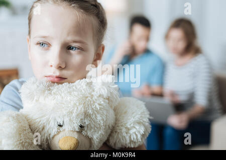 Unhappy little girl hugging her teddy bear Stock Photo