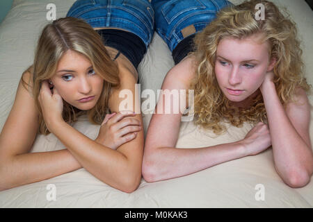 Two teenage girls with blond hair laying on a bed; Connecticut, United States of America Stock Photo
