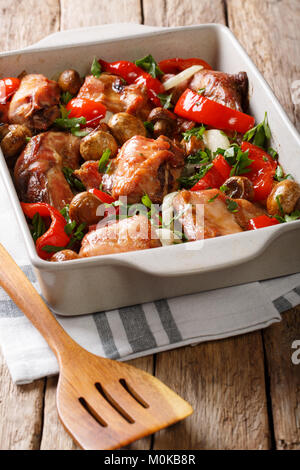 rabbit meat baked with mushrooms, onions and bell peppers close-up in a baking dish on a table. vertical Stock Photo