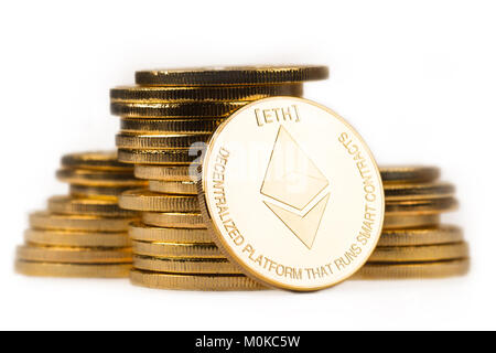 close up golden ethereum in front of a pile of golden metallic coins isolated on white background Stock Photo