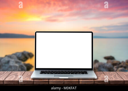 Modern laptop with empty white screen on wooden table against blurred landscape background Stock Photo