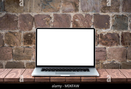 Modern laptop with empty white screen on wooden table against blurred old brick wall Stock Photo