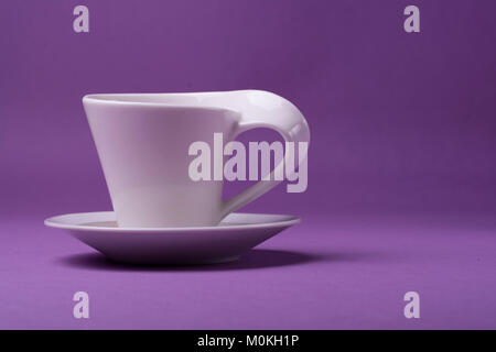 Empty porcelain white cup on purple background. studio shot Stock Photo