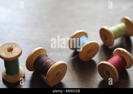 Sewing thread on a wooden background. Set of threads on bobbins  Stock Photo