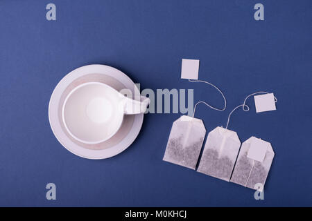Empty Porcelain white cup with three teabags on dark blue background. top view studio shot Stock Photo