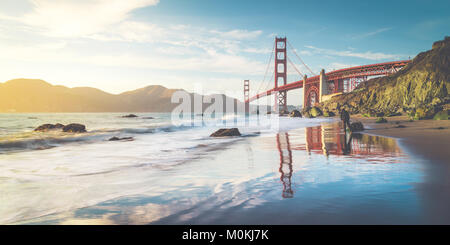 Classic panoramic view of famous Golden Gate Bridge seen from scenic Baker Beach in beautiful golden evening light on a sunny day with blue sky Stock Photo