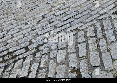 An old fashioned or historic road surface in the form of cobble stones on a cobbled highway. Patterns formed by cobbles or large stones laid for path. Stock Photo