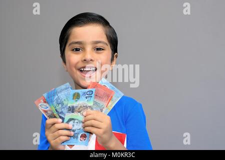 Cheerful kid holding money. Australian dollars in hands of happy child looking at camera. Concept of pocket money. excited child with money. Stock Photo