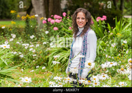 Beautiful smiling model standing amongst flowers in a park in Cork, Ireland. Stock Photo