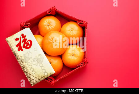 Group of orange tangerine in Chinese pattern tray and envelope packet ang pow on red table top. Chinese new year concep.Chinese Language on envelop is Stock Photo