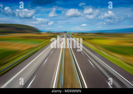 Zoom effect on empty modern highway going through fields Stock Photo