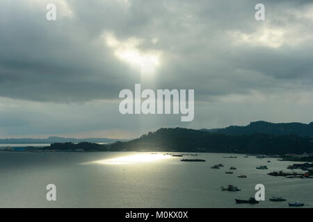 Sunbeams through a cloudy sky over Sandakan Bay, Sulu Sea, Sabah, Borneo, Malaysia Stock Photo