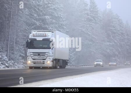 SALO, FINLAND - JANUARY 20, 2018: White Mercedes-Benz Actros semi trailer transports goods along foggy rural highway with cars in winter.