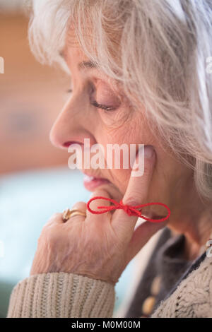 Close Up Of Senior Woman With String Tied Around Finger As Reminder Stock Photo