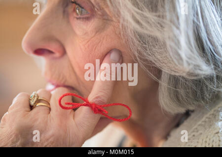 Close Up Of Senior Woman With String Tied Around Finger As Reminder Stock Photo