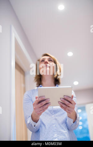 Woman Controlling Lighting With App On Digital Tablet Stock Photo