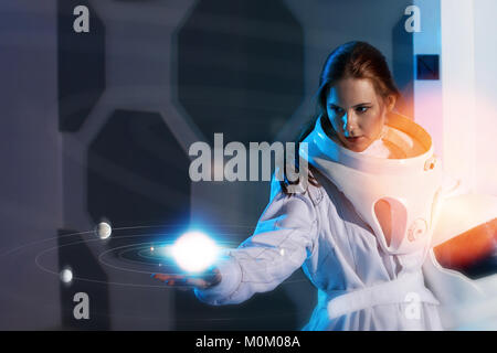 Portrait of a woman astronaut in a space suit, dreamy look up Stock Photo