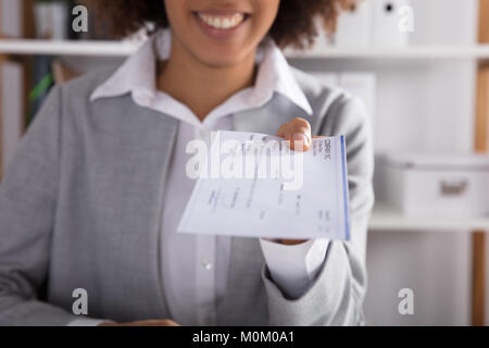 Businessperson Hand Giving Cheque In Office At White Desk Stock Photo