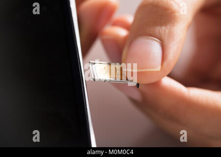 Close-up Of Person's Hand Inserting Micro Sim In Mobile Phone Stock Photo