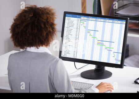 Rear View Of A Businesswoman Working On Gantt Chart On Computer In Office Stock Photo